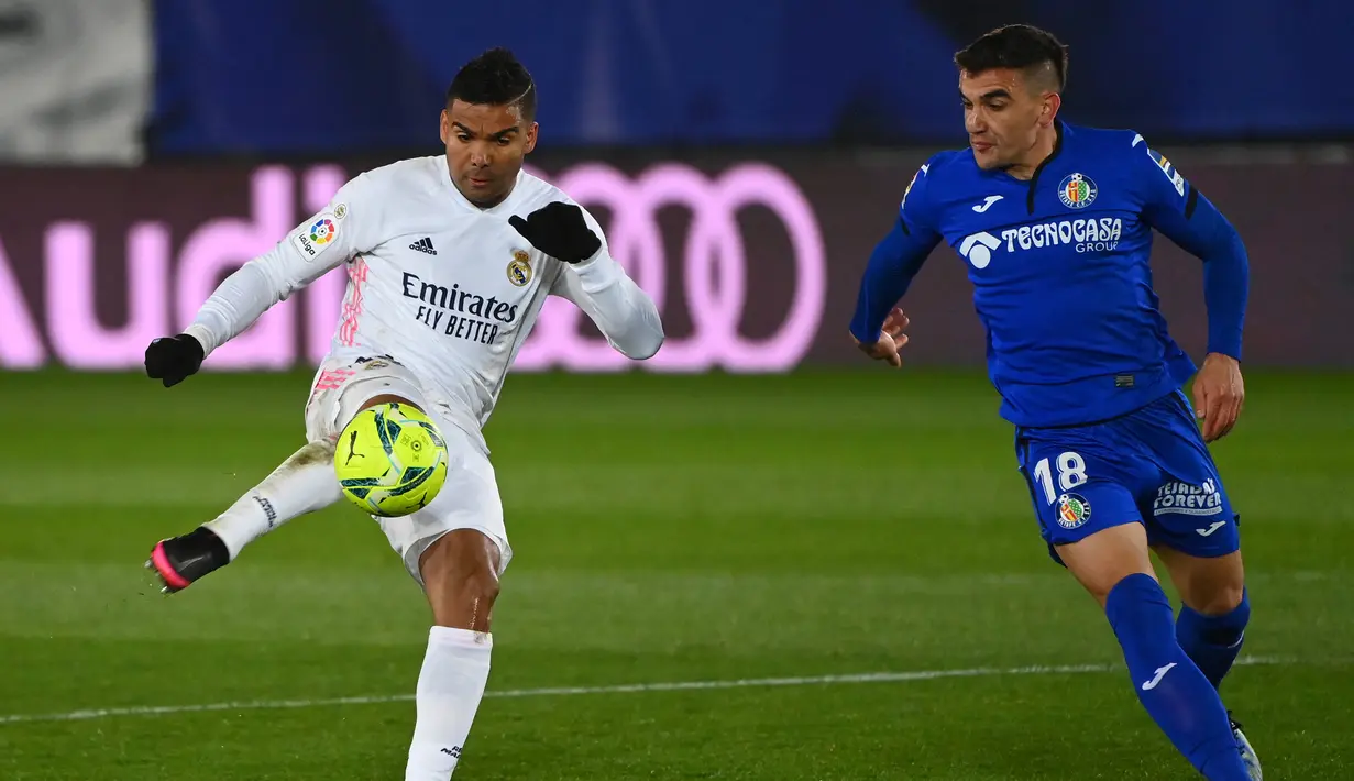 Gelandang Real Madrid, Casemiro (kiri) mengontrol bola dibayangi gelandang Getafe, Mauro Arambarri dalam laga lanjutan Liga Spanyol 2020/21 pekan ke-22 di Alfredo di Stefano Stadium, Selasa (9/2/2021). Real Madrid menang 2-0 atas Getafe. (AFP/Gabriel Bouys)