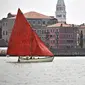 Anggota asosiasi pelayaran budaya berlayar dalam acara Regatta Merah di Venesia, Italia, Minggu (20/6/2021). Acara ini bertujuan untuk merayakan tradisi bahari Venesia kuno dan untuk meningkatkan kesadaran tentang keseimbangan antara kota dan laut. (MARCO BERTORELLO/AFP)