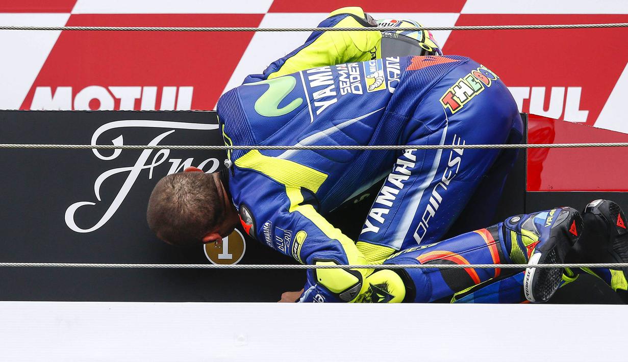 Pebalap Movistar Yamaha, Valentino Rossi, mencium podium usai menjadi yang tercepat pada MotoGP Belanda di Sirkuit Assen, Assen, Minggu (25/6/2017). Riders asal Italia itu memiliki catatan waktu 41 menit 41,149 detik. (AFP/Vincent Jannink) 