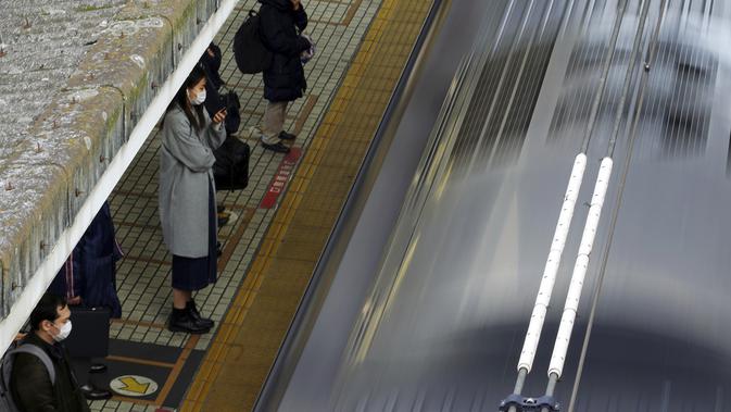 Penumpang mengenakan masker untuk mencegah penyebaran virus corona menunggu kereta di stasiun di Tokyo (8/2/2021). Jumlah infeksi virus corona di Ibu Kota Tokyo, Jepang, meningkat sampai sembilan kali lipat sejak akhir musim panas lalu. (AP Photo/Eugene Hoshiko)