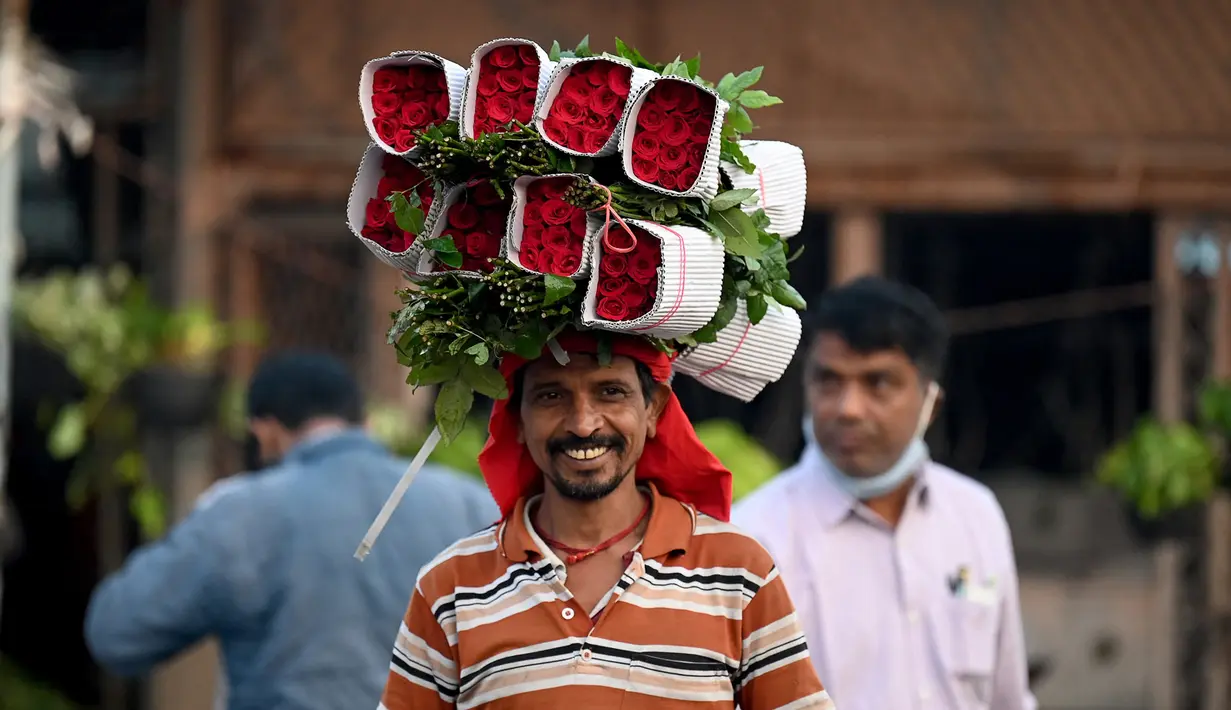 Seorang pedagang membawa seikat mawar jelang Festival Diwali di pasar bunga New Delhi, India, Minggu (31/10/2021). Festival Diwali atau Festival Cahaya dalam agama Hindu melambangkan kemenangan baik atas buruk. (Money SHARMA/AFP)