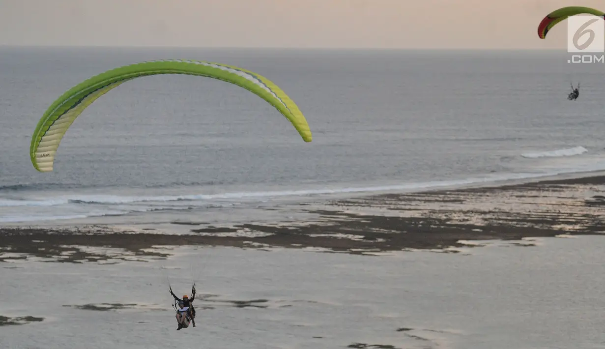 Wisatawan melakukan tandem paralayang yang difasilitasi operator Riug Paragliding di Bukit Riug, Nusa Dua, Bali (30/6). Setiap wisatawan dikenai tarif 110 dollar/ orang untuk penerbangan selama 15 menit. (Merdeka.com/Arie Basuki)