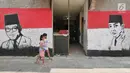 Dua anak melintasi sisi tembok warga yang dindingnya dihiasi lukisan mural Presiden pertama RI, Sukarno di Kampung Pejaten, Jakarta, Senin (30/4). Mural motif warna-warni itu digagas warga untuk memperindah kampung mereka. (Liputan6.com/Herman Zakharia)