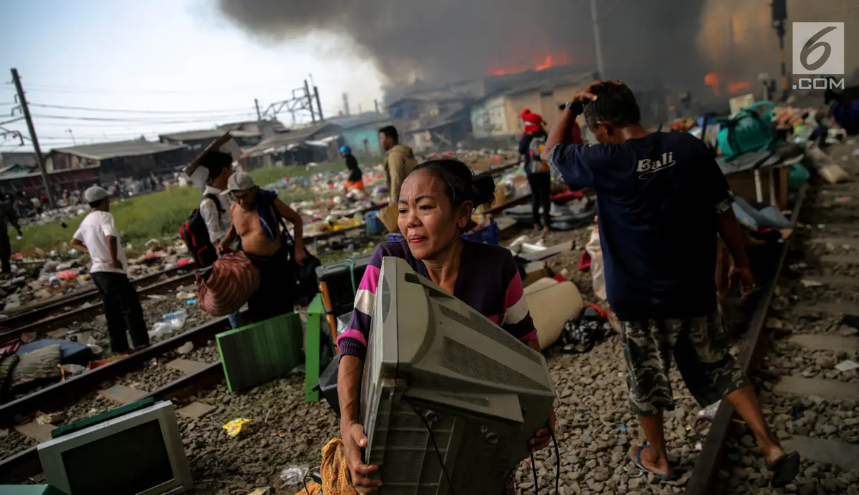 Seorang ibu menyelamatkan sebuah televisi saat kebakaran ratusan rumah bedeng di permukiman liar belakang Hotel Alexis, Pademangan, Jakarta, Sabtu (16/9). Untuk memadamkan api, sebanyak 20 unit pemadam kebakaran dikerahkan. (Liputan6.com/Faizal Fanani)