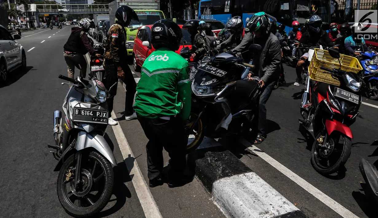 Sejumlah pengendara bergotong royong mengangkat sepeda motor mereka melewati pembatas jalan untuk berpindah jalur di kawasan Ridwan Rais, Jakarta, Rabu (21/8/2019). Pengendara motor tersebut berpindah jalur disebabkan tidak sabar menunggu kemacetan. (Liputan6.com/Johan Tallo)