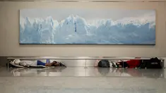 Para tunawisma tidur di bawah foto Gletser Perito Moreno di bandara internasional Jorge Newbery, umumnya dikenal sebagai Aeroparque, di Buenos Aires, Argentina, Kamis, 6 April 2023. (AP Photo/Natacha Pisarenko)