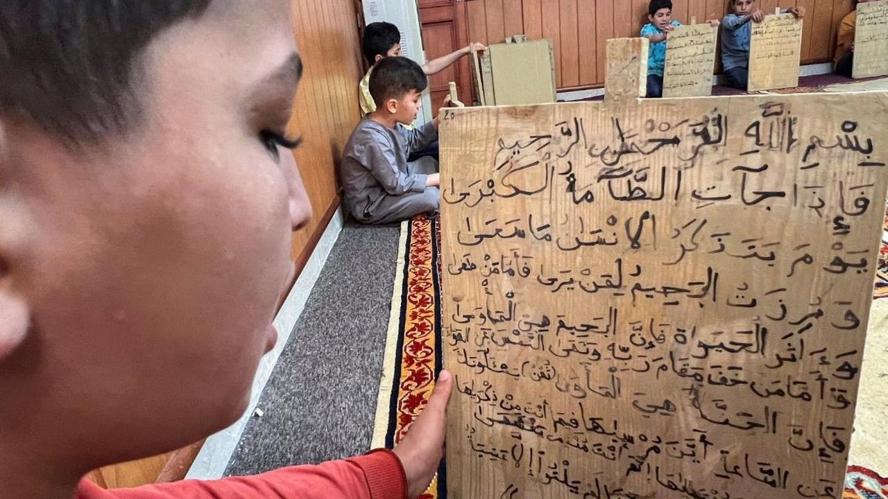 Di sebuah masjid di Tripoli, Libya, sejumlah anak masih belajar membaca dan menulis ayat-ayat Alquran menggunakan cara yang unik, yaitu papan kayu selama bulan suci Ramadhan pada tanggal 3 April 2023. Foto: REUTERS / Ayman al-Sahili<br>