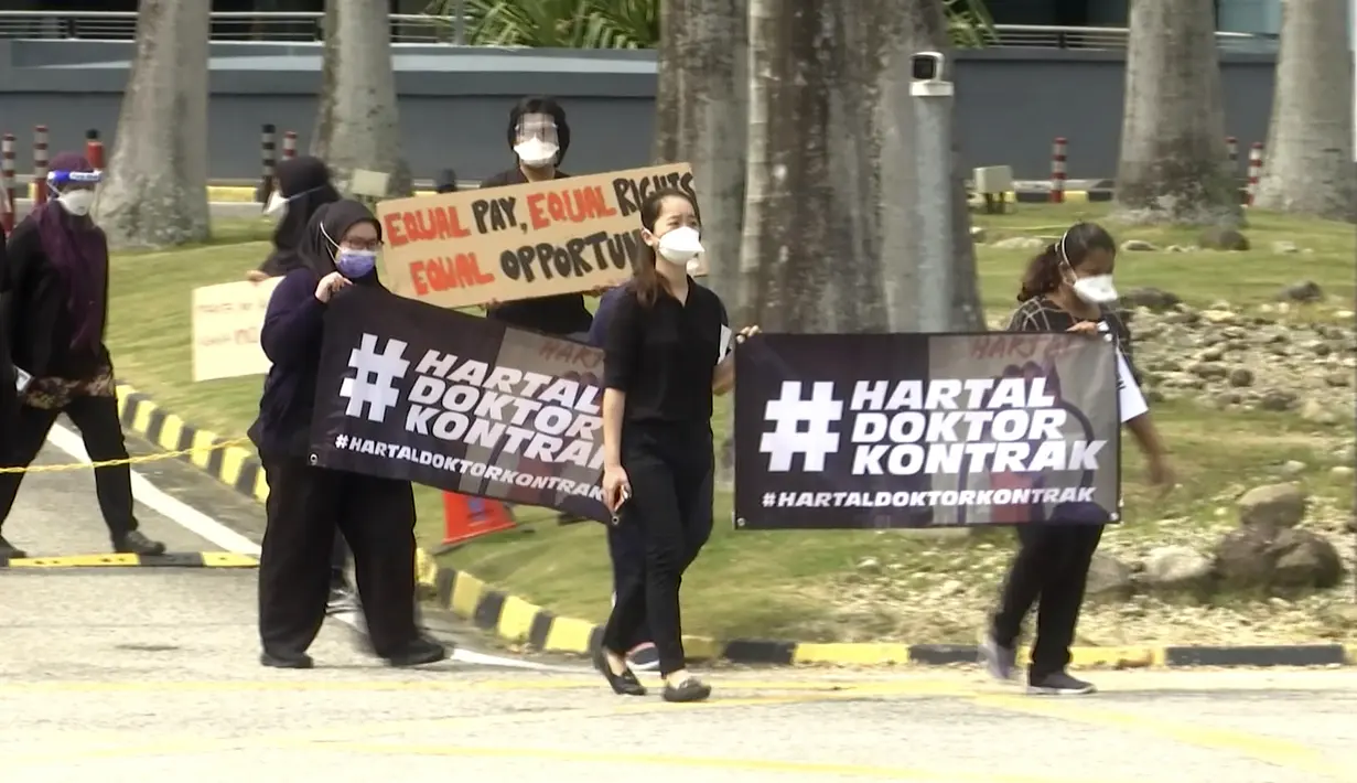 Para dokter memegang spanduk bertuliskan "Pemogokan Dokter Kontrak" saat berpartisipasi dalam aksi mogok di Rumah Sakit Sungai Buloh di Selangor, Malaysia ,Senin (26/7/2021). Ratusan dokter melakukan aksi mogok kerja dari rumah sakit pemerintah Malaysia pada (26/7).  (AP Photo)