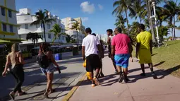 Orang-orang berjalan di sepanjang Ocean Drive di Miami Beach, Florida, Selasa (16/3/2021). Mahasiswa telah tiba di daerah Florida Selatan untuk liburan musim semi. Para pejabat kota prihatin dengan kerumunan liburan musim semi saat pandemi COVID-19 terus berlanjut. (Joe Raedle/Getty Images/AFP)