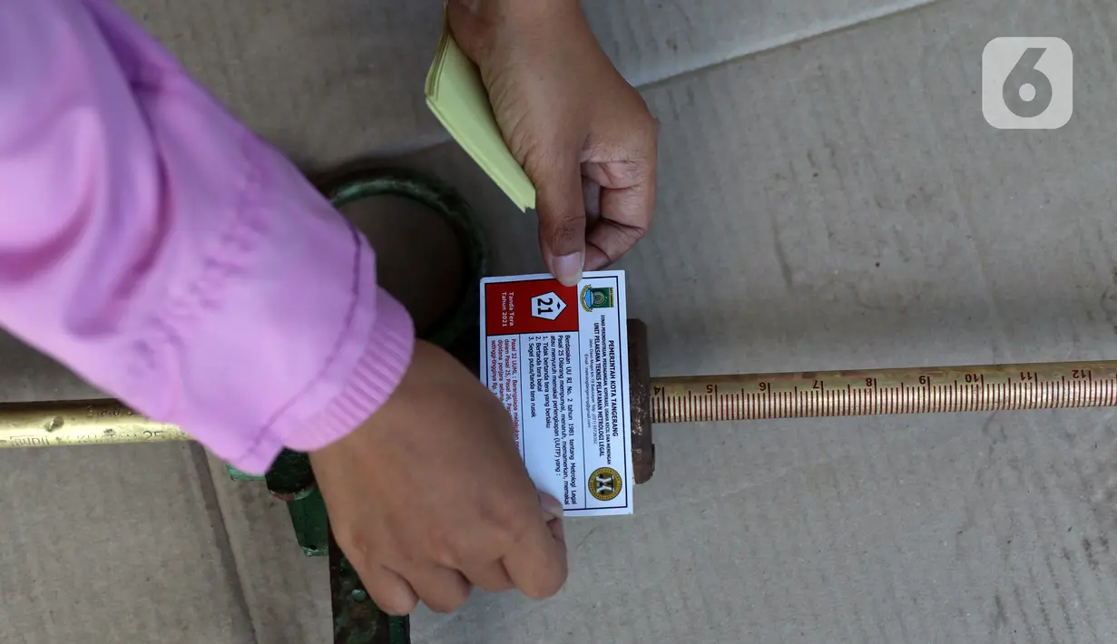 Petugas UPT Disperindagkop UKM Kota Tangerang menempelkan stiker pada alat ukur timbangan saat sidak di Kecamatan Larangan, Kota Tangerang, Banten, Kamis (2/12/2021). Pengecekan dilakukan untuk memastikan alat ukur tersebut tidak ada kesalahan. (Liputan6.com/Angga Yuniar)