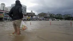 Seorang warga berjalan melewati banjir di Gangneung, Korea Selatan, Kamis (3/9/2020). Lebih dari 2.200 orang dievakuasi ke tempat penampungan sementara. (Lee Hae-yong/Yonhap via AP)