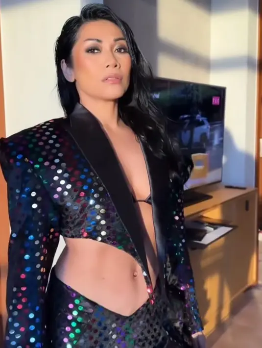 Hingga tiba di pertengahan lagu, wanita 49 tahun itu tiba-tiba membuka jubahnya, memperlihatkan perut ratanya dengan mengenakan set sequin crop blazer, bra, dan asymmetric skirt, dan high heels boots berkilau. [Foto: IG/anggun_cipta]