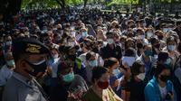 Polisi melakukan pengamanan saat warga menunggu dalam antrean untuk mendaftar vaksin virus corona COVID-19 AstraZeneca di Denpasar, Bali, Sabtu (26/6/2021). Ratusan warga terlihat antusias mengikuti vaksinasi massal ini. (SONY TUMBELAKA/AFP)