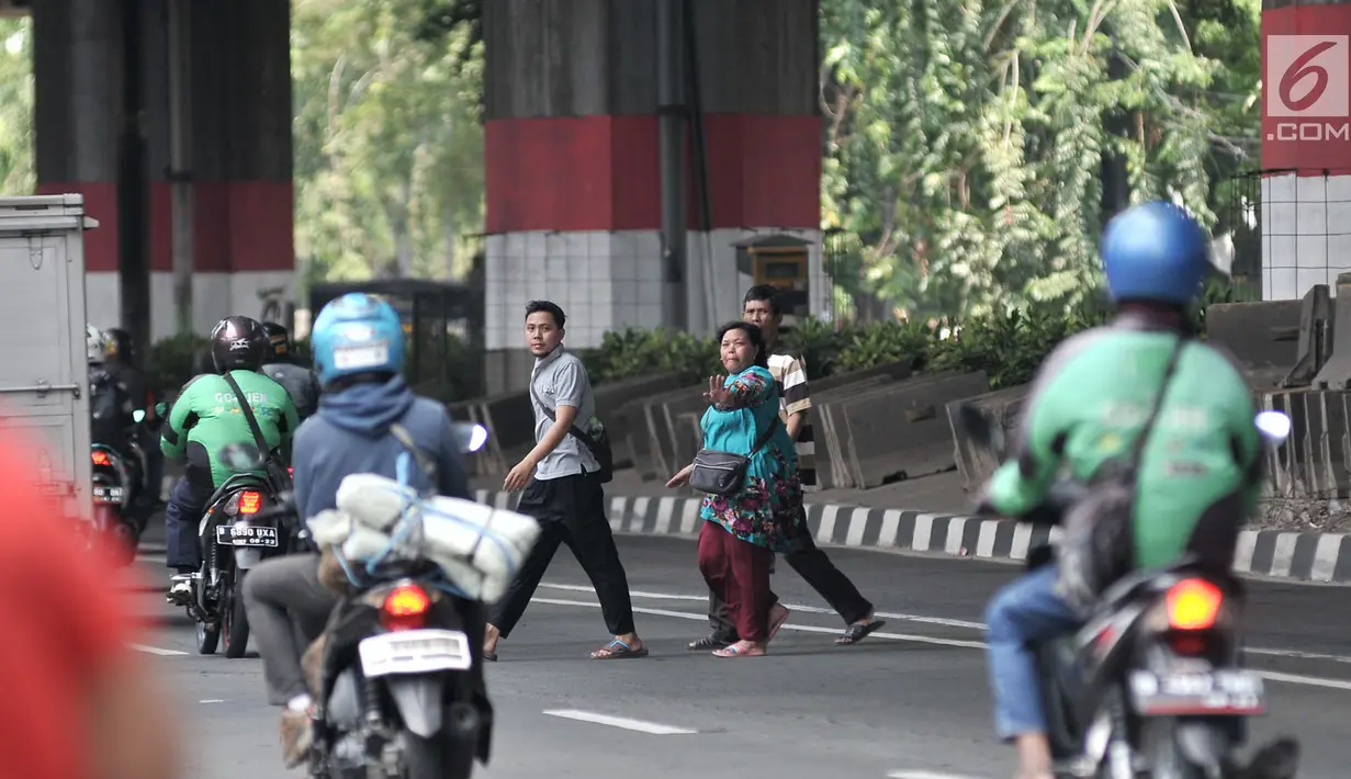 Pejalan kaki menyeberangi jalan di JPO di Prumpung, Jakarta, Selasa (18/9). Minimnya kesadaran warga menyeberangi jalan tanpa menggunakan JPO dapat membahayakan keselamatan serta menyebabkan kecelakaan.(merdeka.com/ Iqbal S. Nugroho)