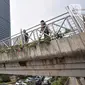 Pejalan kaki melintas di jembatan penyeberangan orang (JPO) yang tidak beratap di jalan Sudirman, Jakarta, Rabu (6/11/2019). Pemprov DKI melalui Dinas Bina Marga mencopot atap JPO Sudirman agar pejalan kaki dapat menikmati pemandangan gedung-gedung pencakar langit. (merdeka.com/Iqbal Nugroho)