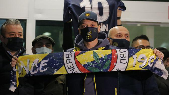 Gelandang Jerman, Mesut Ozil membentangkan syal klub barunya Fenerbahce setibanya di Bandara Ataturk di Istanbul (18/1/2021). Ozil yang merupakan keturunan Turki akan berusaha menghidupkan kembali karirnya setelah dia meninggalkan Arsenal. (AP Photo)