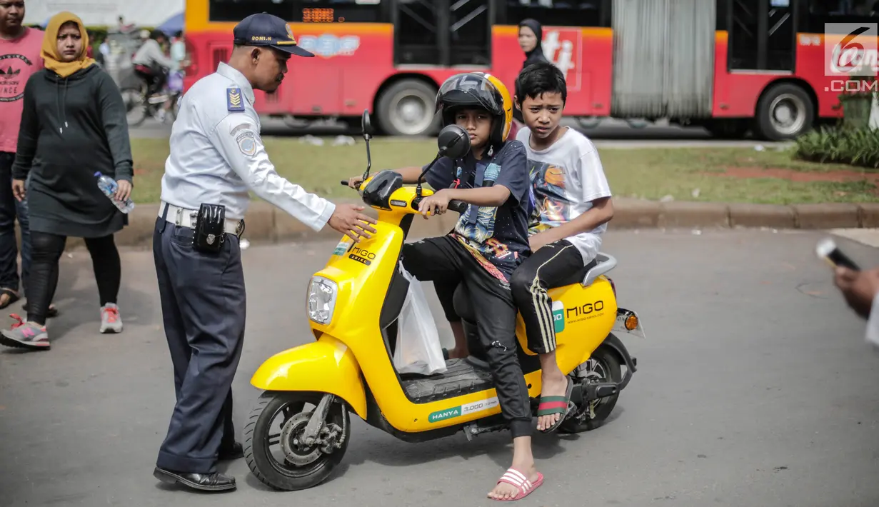 Petugas Dishub mensosialisasikan kepada pengendara sepeda motor listrik Migo saat melintasi CFD di kawasan Bundaran HI, Jakarta, Minggu (17/2). Penyewa sepeda motor listrik dihimbau untuk tidak melintasi jalan raya. (Liputan6.com/Faizal Fanani)