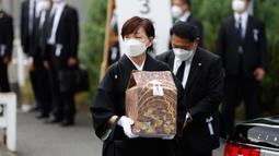 Akie Abe, istri mantan Perdana Menteri Shinzo Abe, membawa guci berisi abu mendiang suaminya saat tiba di tempat pemakaman kenegaraan di Nippon Budokan, Tokyo, Jepang, Selasa (27/9/2022). Biaya tersebut mencakup 800 juta Yen (Rp 83,9 miliar) untuk keamanan dan 600 juta Yen (Rp 62,9 miliar) untuk menjamu delegasi asing. (Kiyoshi Ota/Pool Photo via AP)