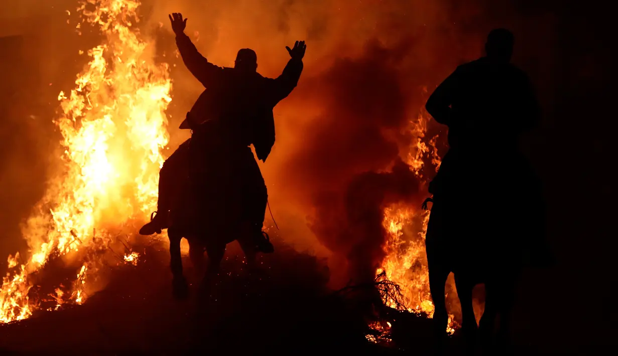 Seorang pria menunggangi kuda melewati api unggun saat festival Luminarias di San Bartolome de Pinares, Spanyol, Jumat (16/1/2020). Festival keagamaan itu sebaga bagian dari ritual untuk menghormati San Antonio Abad (Santo Anthony), santo pelindung binatang. (AP Photo/Manu Fernandez)