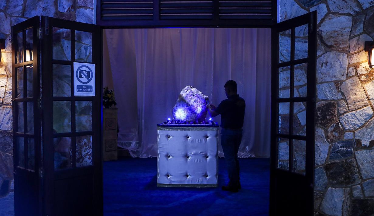 Seorang pria Sri Lanka mengambil foto safir biru korundum alami seberat 310 kilogram di Horana, sekitar 41 km dari selatan Kolombo, pada 12 Desember 2021. Kendati demikian oganisasi internasional belum mengesahkannya sebagai yang terberat di dunia. (AP Photo/Eranga Jayawardena)
