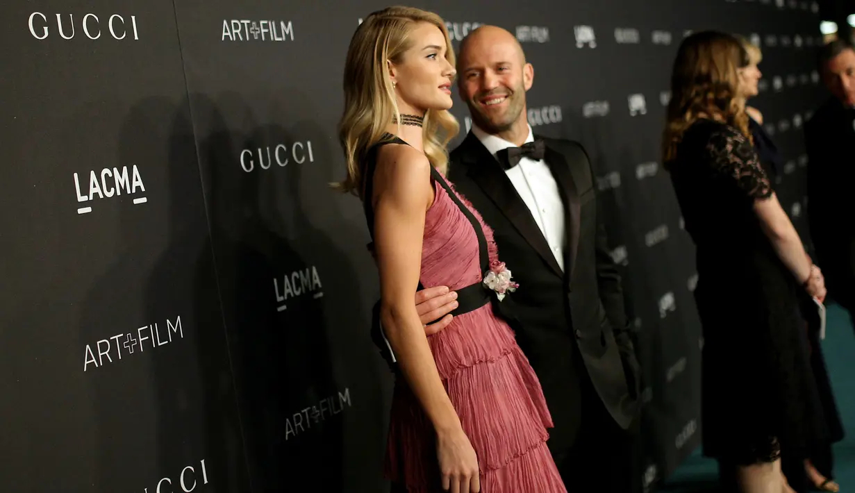 Model dan aktris Rosie Huntington -Whiteley berpose bersama sang kekasih, aktor Jason Statham saat menghadiri gala LACMA Art + Film di Los Angeles, California, Minggu (7/11). (Jason Merritt/Getty Images untuk LACMA / AFP)