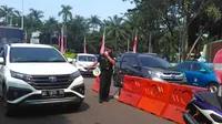 Seorang Petugas Tengah Mengatur Antrean Kendaraan di Gerbang Taman Mini Indonesia Indah (TMII), Jakarta, Sabtu (8/6/2019). (Foto: Muhammad Radityo Priyasmoro/Liputan6.com)