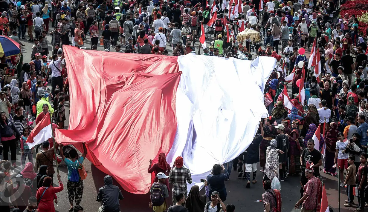 Peserta membentangkan bendera merah putih raksasa pada Karnaval Cinta Budaya NKRI di MH Thamrin, Jakarta, Minggu (20/11). Ribuan peserta yang terdiri dari berbagai elemen membawa dan mengibarkan bendera merah putih. (Liputan6.com/Faizal Fanani)
