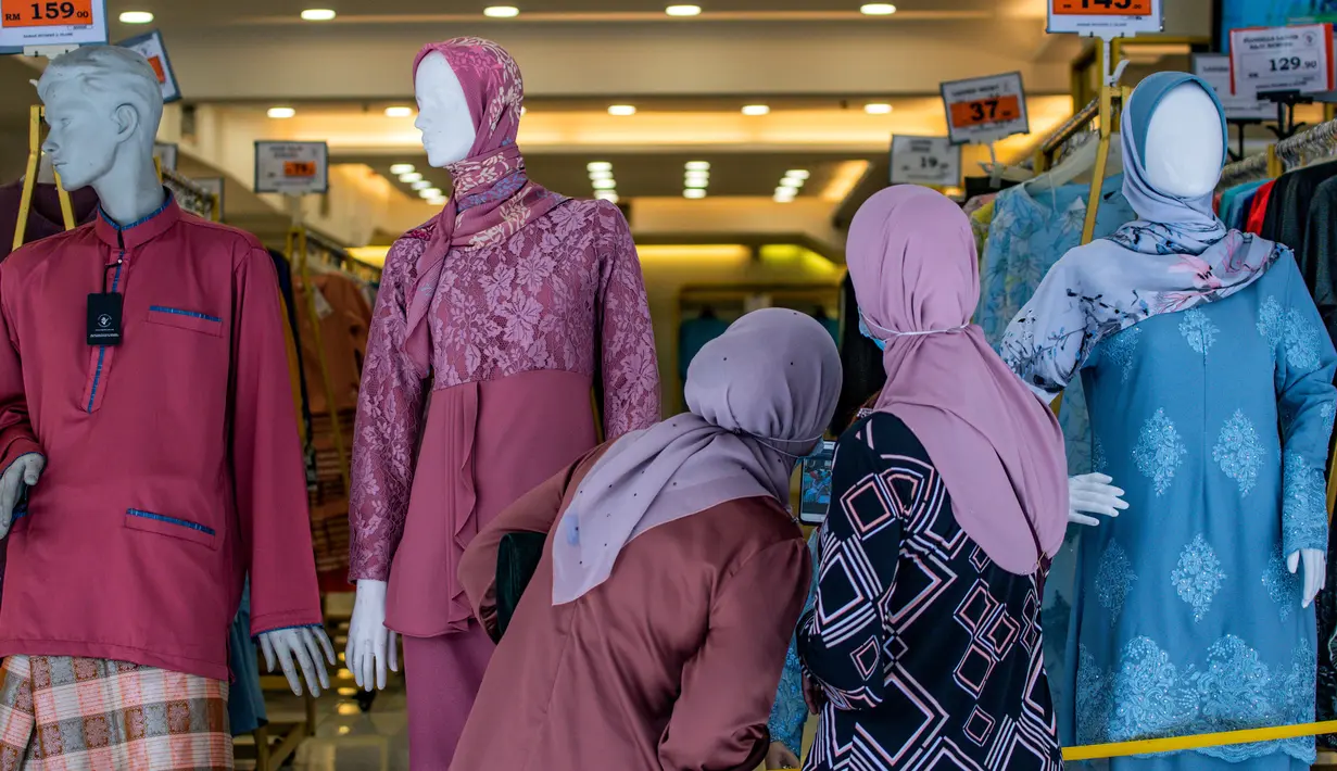 Wanita Muslim melihat ke sebuah toko yang menjual pakaian budaya Malaysia yang disebut baju melayu dan baju kurung menjelang  Idul Fitri yang menandai berakhirnya bulan suci Ramadan di Kuala Lumpur (13/5/2020). (AFP/Mohd Rasfan)