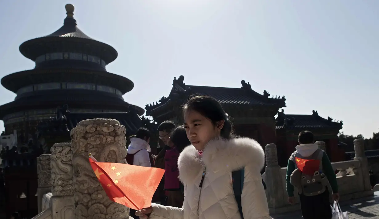 Seorang gadis memegang bendera nasional China saat ia mengunjungi Kuil Surga selama liburan Tahun Baru Imlek di Beijing (20/2). Warga China tengah liburan selama seminggu yang menandai dimulainya Tahun Anjing. (AFP Photo/Nicolas Asfouri)
