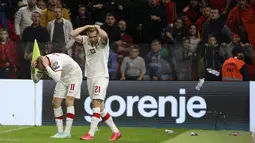 Penyerang Polandia Karol Swiderski (kiri) memegangi kepalanya saat suporter melemparkan botol tak lama setelah mencetak gol ke gawang Albania pada lanjutan Kualifikasi Piala Dunia 2022, di Air Albania Stadium, Rabu (13/10/2021) dini hari WIB. Polandia mengalahkan Albania 1-0. (AP Photo/Franc Zhurda)