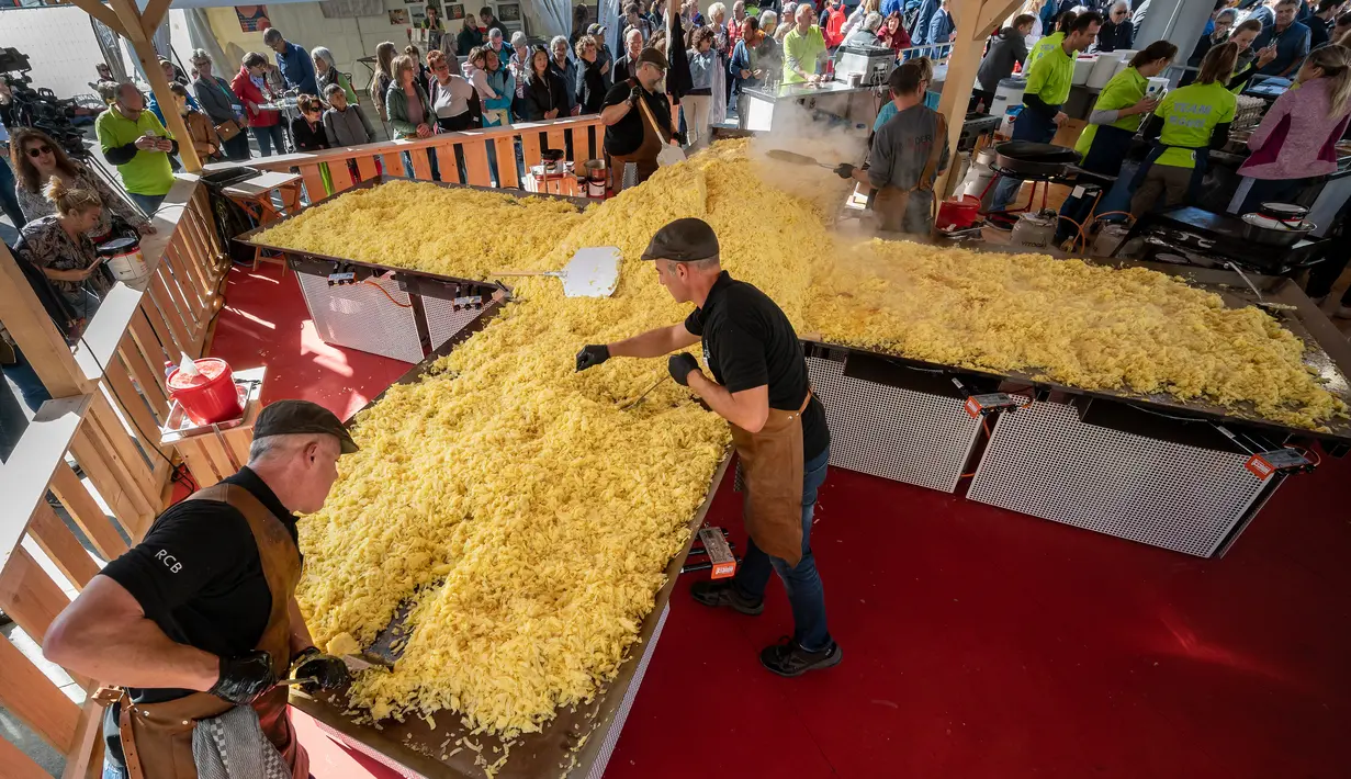Koki memasak rosti dalam upaya memecahkan rekor dunia saat acara yang menandai peringatan 125 tahun Serikat Petani Swiss (SBV) di Bern, Swiss pada 19 September 2022. Sebagian dari rosti itu kemudian dibagikan kepada warga yang menonton acara itu. (Fabrice COFFRINI / AFP)