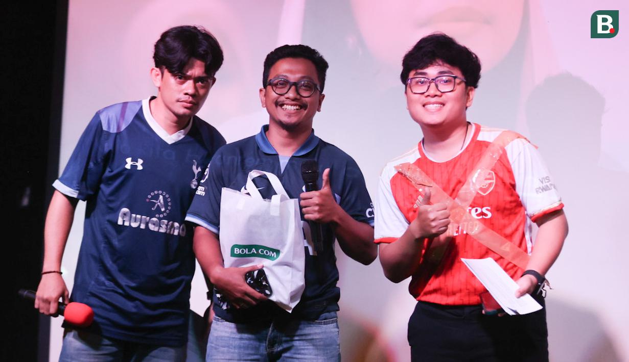 Seorang peserta kuis yang beruntung (tengah) mendapatkan merchandise dari sponsor berfoto bersama MC dalam acara Roaring Night Liga Inggris 2023/2024 antara Tottenham Hotspur kontra Arsenal di Treehaus Kemang, Minggu (28/4/2024) malam WIB yang digelar komunitas penggemar Tottenham Hotspur, IndoSpurs Jakarta. (Bola.com/Abdul Aziz)
