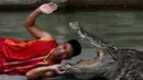 Seorang pria beratraksi dengan meletakkan kepalanya kedalam mulut buaya di Sriracha Tiger Zoo, Provinsi Chonburi , Thailand , 7 Juni 2016. Aksi nekat ini mengundang decak kagum wisatawan yang hadir. (REUTERS / Chaiwat Subprasom)