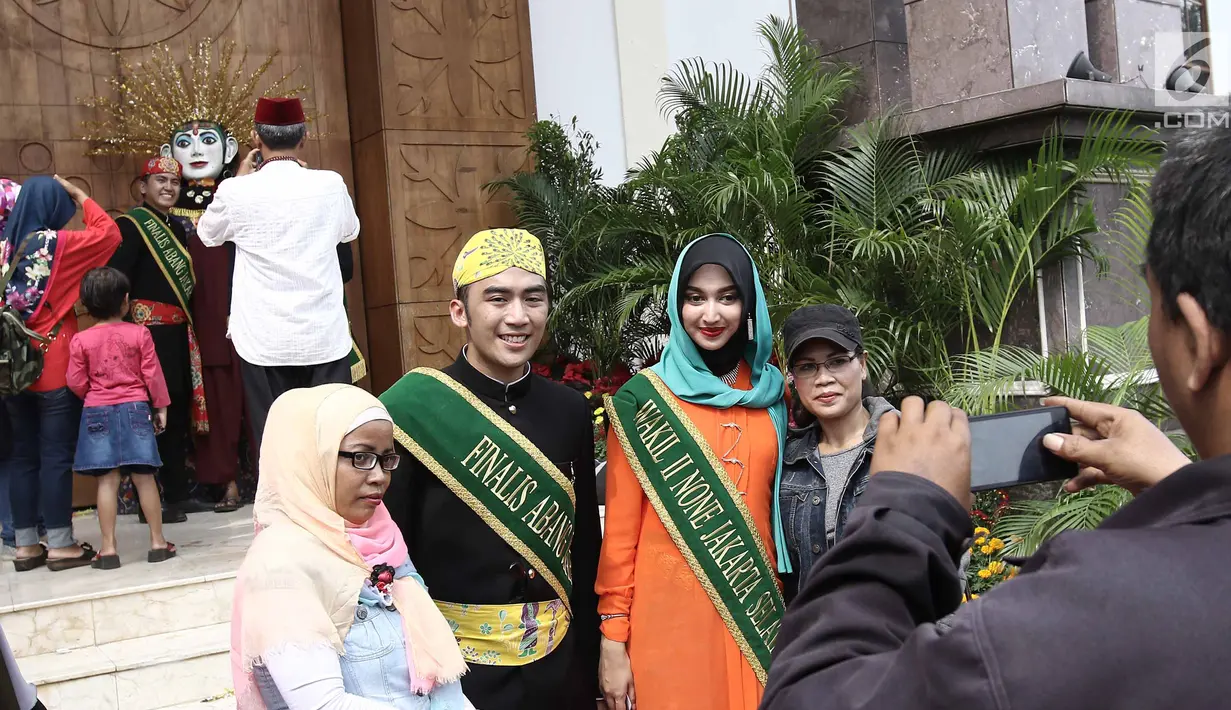 Pengunjung berfoto bersama finalis Abang None pada Festival Lebaran Betawi 2017 di Setu Babakan, Jakarta, Sabtu (29/7). Berbagai pergelaran seni dan adat Betawi disiapkan untuk menghibur para pengunjung yang datang. (Liputan6.com/Herman Zakharia)