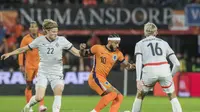 Memphis Depay dari Belanda, tengah, ditantang oleh Andri Gudjohnsen dari Islandia, kiri, selama pertandingan sepak bola persahabatan internasional antara Belanda dan Islandia di stadion De Kuip di Rotterdam, Belanda, Senin, 10 Juni 2024. (AP Photo/Patrick Post)