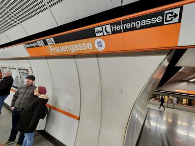 Para pelancong menunggu kereta bawah tanah U3 mereka di stasiun Herrengasse (Jalan Pria) yang ditutup dengan tanda sementara Frauengasse (Jalan Wanita) untuk merayakan Hari Perempuan Internasional di Wina, Austria, Rabu (8/3/2023). Dalam bahasa Inggris, ini berarti mengubah nama dari "Men's Lane" menjadi "Women's Lane". (JOE KLAMAR / AFP)
