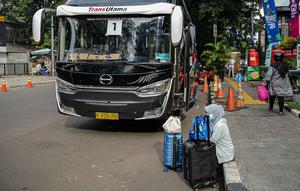 Seorang warga dengan barang bawaannya menunggu untuk menaiki bus mudik bareng gratis BUMN di kawasan Jakarta, Rabu (27/4/2022). Program mudik gratis merupakan salah satu solusi untuk mengantisipasi potensi kepadatan lalu lintas pada masa Lebaran.(Liputan6.com/Faizal Fanani)