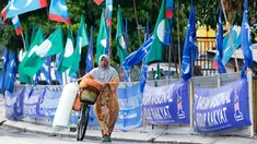 Seorang wanita mendorong sepedanya di samping bendera-bendera partai politik, Kuala Lumpur, Malaysia, Senin (7/5). Malaysia akan melangsungkan pemilu pada 9 Mei 2018. (AP Photo/Aaron Favila)