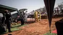 Para pengurus dari rumah duka AVBOB mendorong peti mati selama pemakaman jenazah pasien virus corona COVID-19 di pemakaman Olifantsvlei, Soweto, Afrika Selatan, 21 Juli 2020. (MARCO LONGARI/AFP)