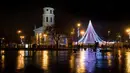 Pesepeda melintas depan pohon Natal raksasa yang berdiri di Alun-Alun Katedral di Vilnius, Lithuania, 1 Desember 2017. Konstruksi pohon ini menutupi area sekitar 2500 meter persegi dan diharapkan bisa menarik banyak pengunjung. (AP Photo/Mindaugas Kulbis)