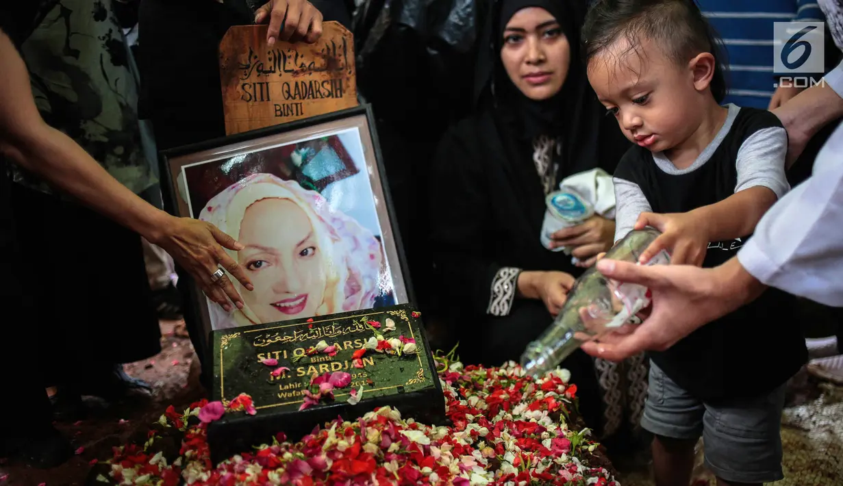 Cucu aktris senior Titi Qadarsih menuangkan air ke pusara sang nenek saat pemakaman di TPU Tanah Kusir, Jakarta, Selasa (23/10). Titi menghembuskan nafas terakhir pada Senin, 22 Oktober 2018. (Liputan6.com/Faizal Fanani)