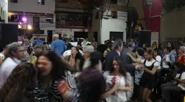 Orang-orang menari selama peresmian festival film pertama yang menampilkan film-film Venezuela di lingkungan San Agustín di Caracas, Venezuela (23/5/2022). Warga di San Agustin telah mengadakan acara budaya seperti ini selama bertahun-tahun, untuk mengubah budaya mereka yang dulu. (AP Photo/Ariana Cubillos)
