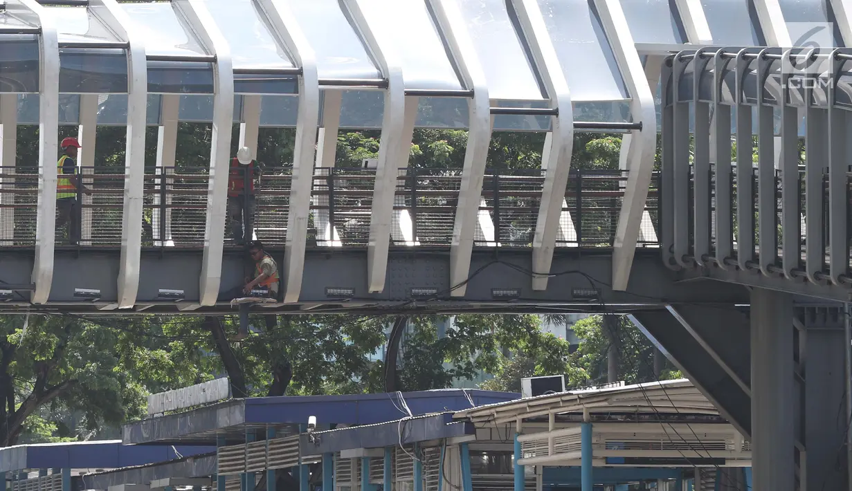 Pekerja beraktivitas mengerjakan proses revitalisasi JPO Gelora Bung Karno di Jalan Jenderal Sudirman, Jakarta, Jumat (22/2). Ditarget selesai pada Januari 2019, hingga kini proses revitalisasi masih terus berjalan. (Liputan6.com/Helmi Fithriansyah)