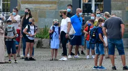 Para orang tua bersama anak mereka menunggu di halaman sekolah untuk memulai hari pertama mereka di Gelsenkirchen, Jerman, Rabu (12/8/2020). Para siswa di negara bagian Jerman, North Rhine-Westphalia, harus mengenakan masker setiap waktu ketika mereka kembali ke sekolah. (AP Photo/Martin Meissner)