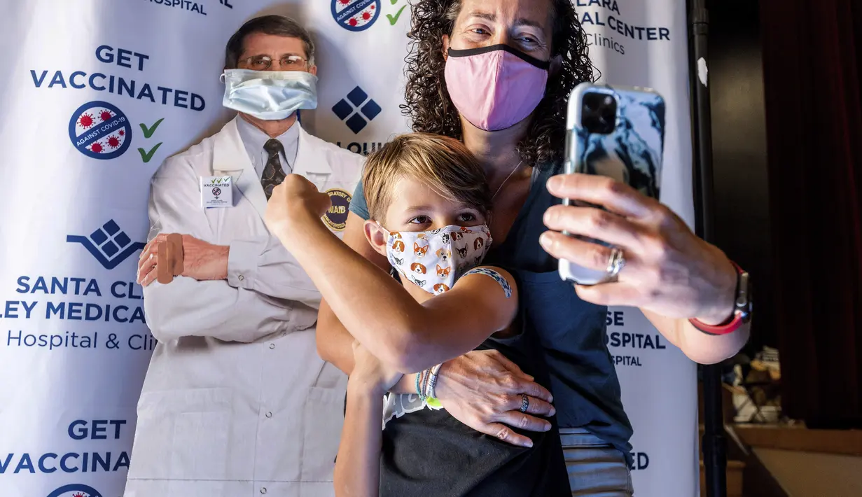 Finn Washburn (9) dan ibunya, Kate Elsley mengambil foto setelah menerima vaksin COVID-19 Pfizer-BioNTech pada hari pertama vaksinasi anak 5 - 11 tahun di San Jose, California, Rabu(3/11/2021). Ini menjadi langkah perdana vaksinasi Covid-19 bagi anak kecil di Amerika Serikat. (AP Photo /Noah Berger)