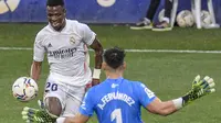 Winger Real Madrid Vinicius Junior coba menaklukkan kiper Huesca Alvaro Fernandez pada laga Liga Spanyol di Estadio El Alcoraz, Sabtu (6/2/2021). (AP Photo/Alvaro Barrientos)