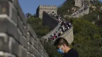 Seorang pria yang mengenakan masker untuk membantu melindungi dari virus corona berdiri di dekat hamparan Tembok Besar China di pinggiran Beijing (6/10/2020). (AP Photo/Ng Han Guan)