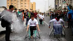 Para peserta saat bersaing mencapai garis finis dalam perlombaan kursi roda di Kota Gaza, (29/11). Lomba ini diselenggarakan untuk para warga yang mengalami cacat fisik akibat konflik sejak tahun 2008 dengan militer Israel. (REUTERS/Suhaib Salem)
