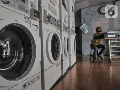 Pekerja duduk di bangku kasir saat menunggu pelanggan di Jaksa Clean Coin Laundry, Jalan Jaksa, Jakarta, Kamis (1/4/2021). Akibat pandemi Covid-19, jasa cuci pakaian mandiri atau self service mengalami sepi pelanggan mencapai 50 persen. (merdeka.com/Iqbal S Nugroho)