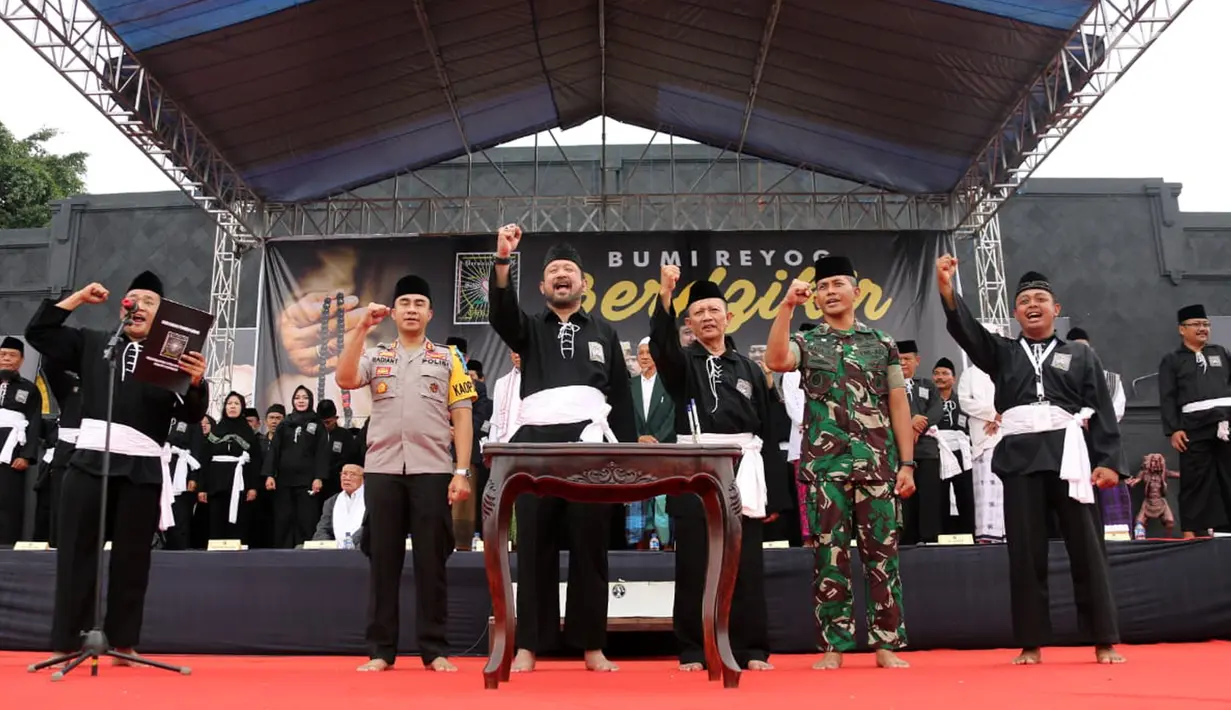 Anam Ardiansyah (kiri) memimpin Deklarasi Pemilu Damai diikuti Bupati Ponorogo Ipong Muchlissoni (tengah) dan 45.024 pesilat PSHT dari 307 desa dan kelurahan di Alun-alun Ponorogo, Jawa Timur, Minggu (30/12). (Liputan6.com/HO/Firdaus)